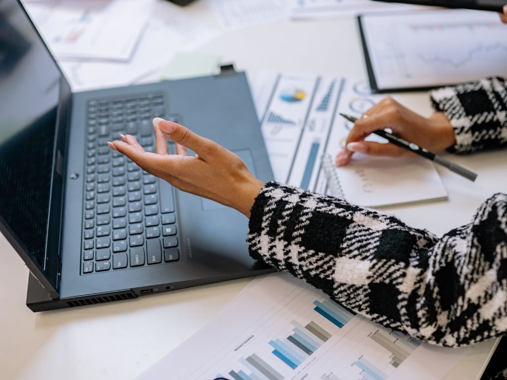 Printed reports spread across a desk beside a laptop