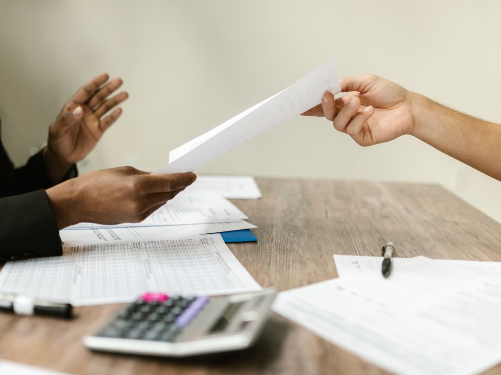 A paper file handed across a desk